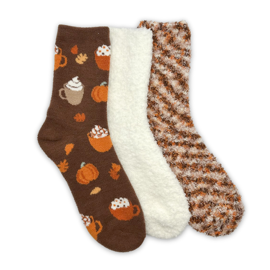 Three socks with the first containing fall themed pumpkin drink on a dark brown background. The second sock in white and the third in brown pattern.
