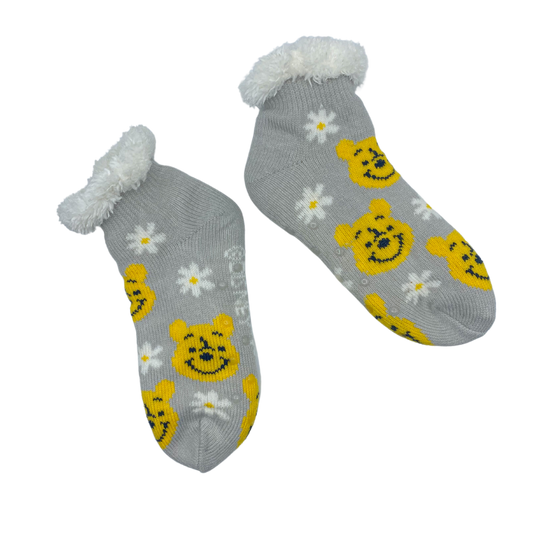 One grey cozy warmer sock featuring an alternating pattern of Winnie the Pooh face in its original color and a white seven-petaled flower with an yellowish orange core.