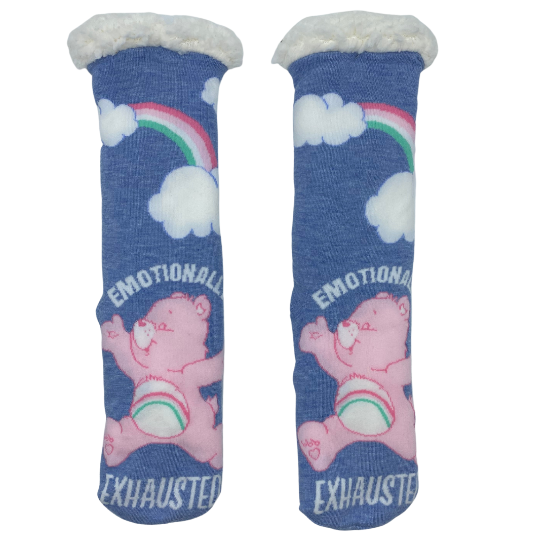 One pair of sock featuring a pink Care Bear with the phrase "Emotionally exhausted" appearing around him. Above that are two clouds joined by a rainbow.
The sock features rubber dot grippers on the bottom and a white sherpa lined cuff.